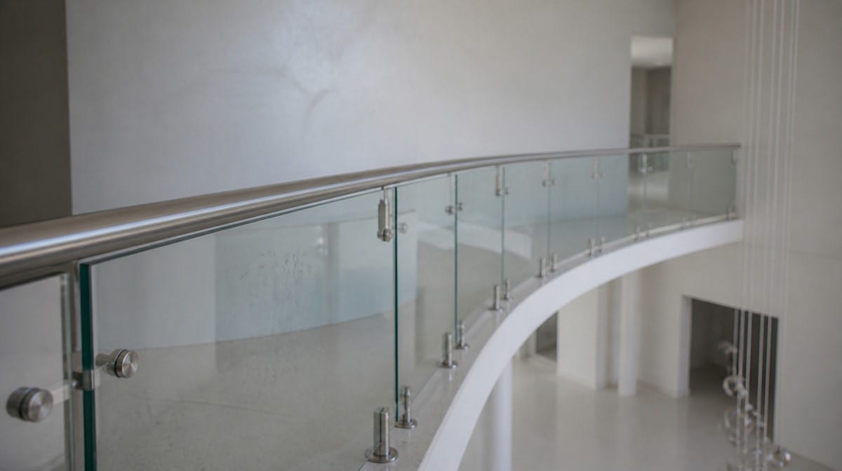Continuous stainless handrail running the full length of a curved railing